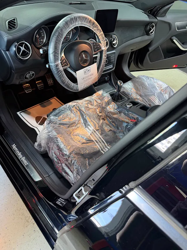 Fertig gereinigter Mercedes-Innenraum mit Schutzfolien auf Lenkrad und Sitz und einer Dankeskarte von Wash & Drive