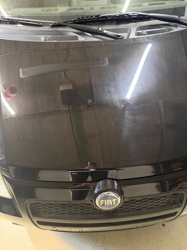 Motorhaube eines Fiat, eine Hälfte poliert und spiegelnd, die andere noch mit Kratzern